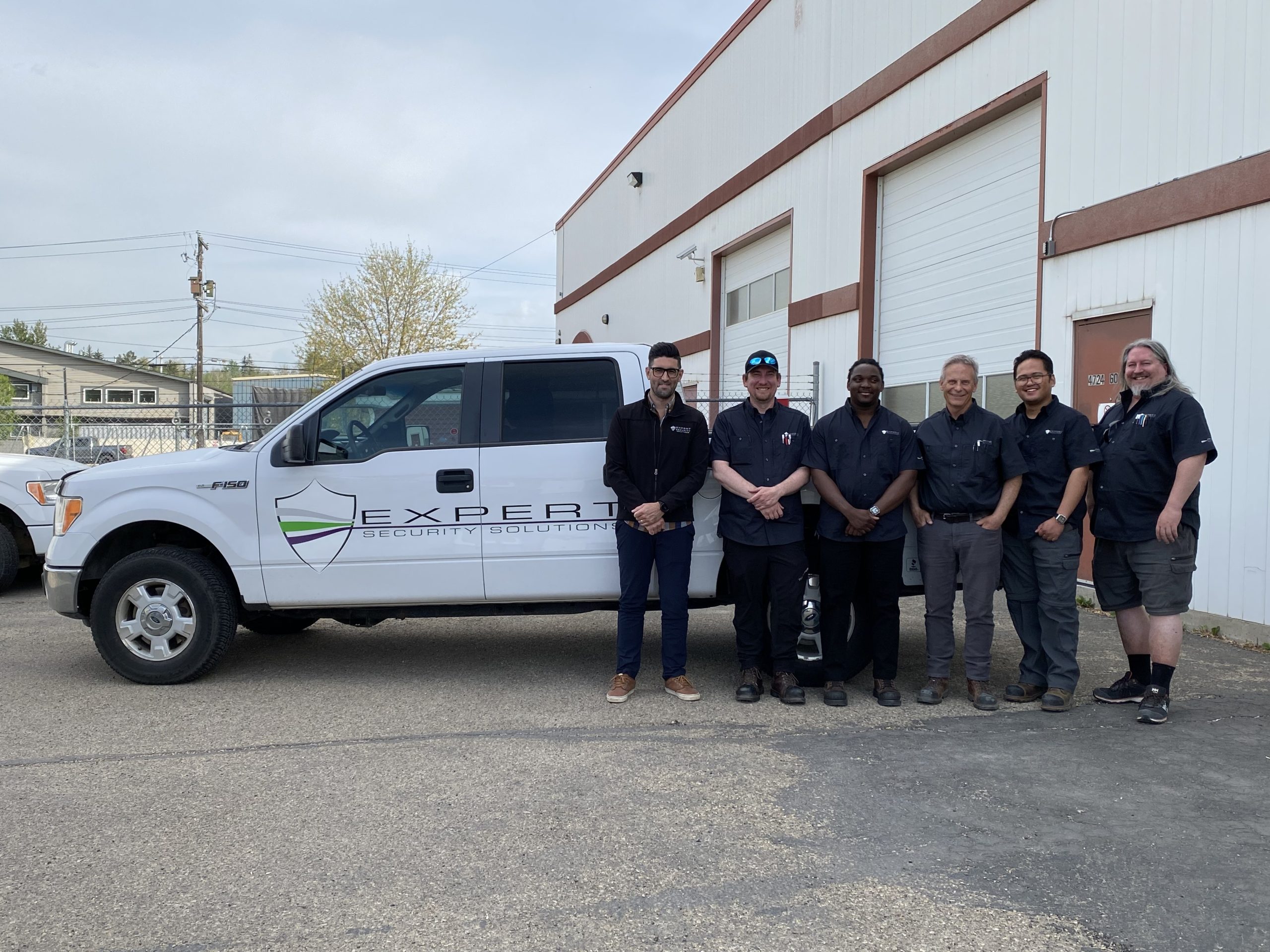 The team at Expert Security Solutions standing in front of their service truck. 